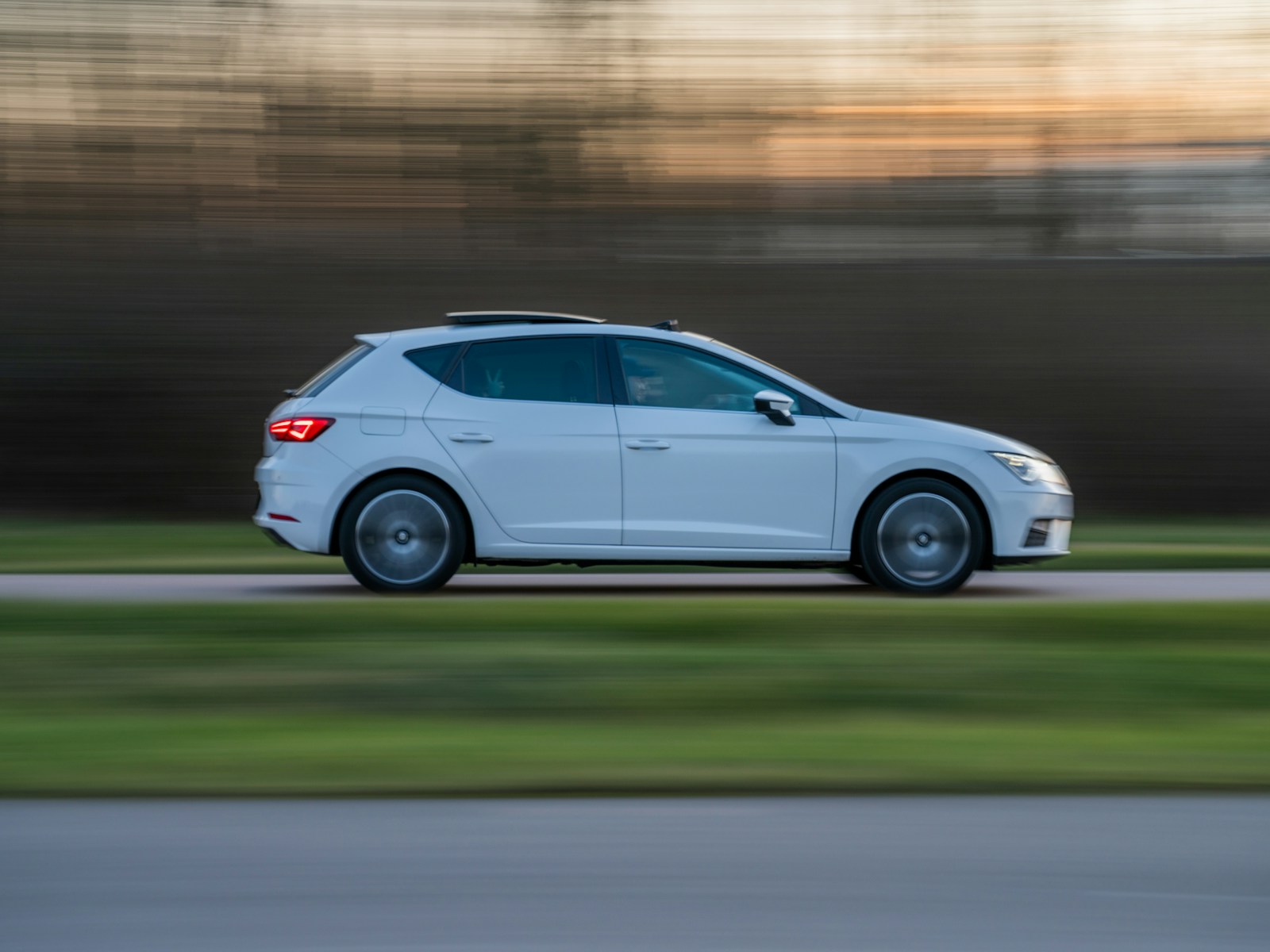 White hatchback driving along a road